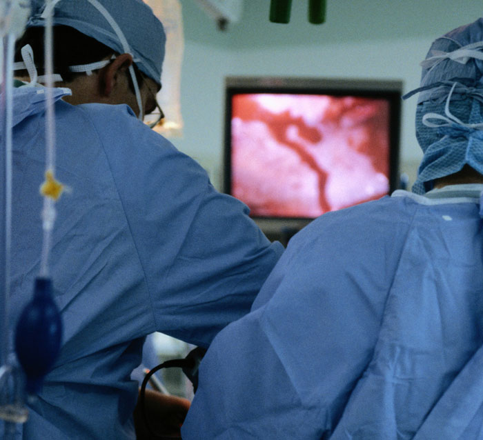 Two medical professionals in surgical attire performing procedure, person thinks DNA test mixed concept visualized.