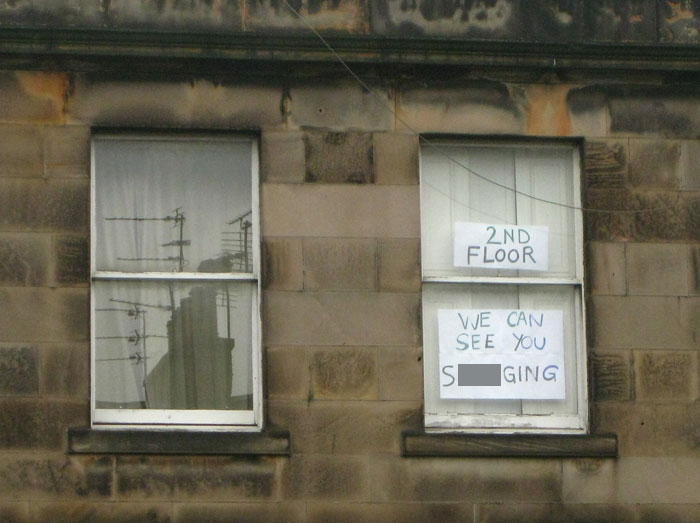 Two handwritten neighbor notes taped to a second-floor window, illustrating unhinged neighbor behavior.