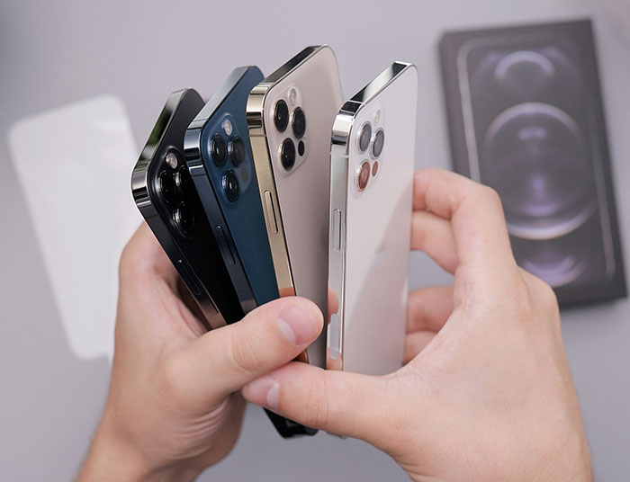 Person holding multiple iPhones in different colors, showcasing a collection of 26 iPhones glued to the body concept. - 4