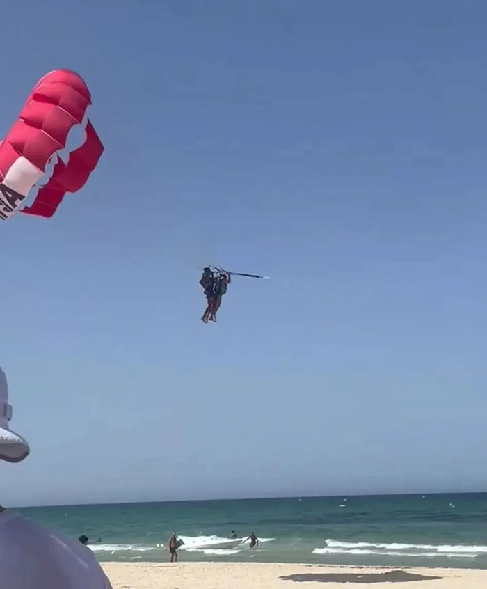 Parasailing over the ocean with two people harnessed mid-air, illustrating a mid-air assault incident keyword. - 9