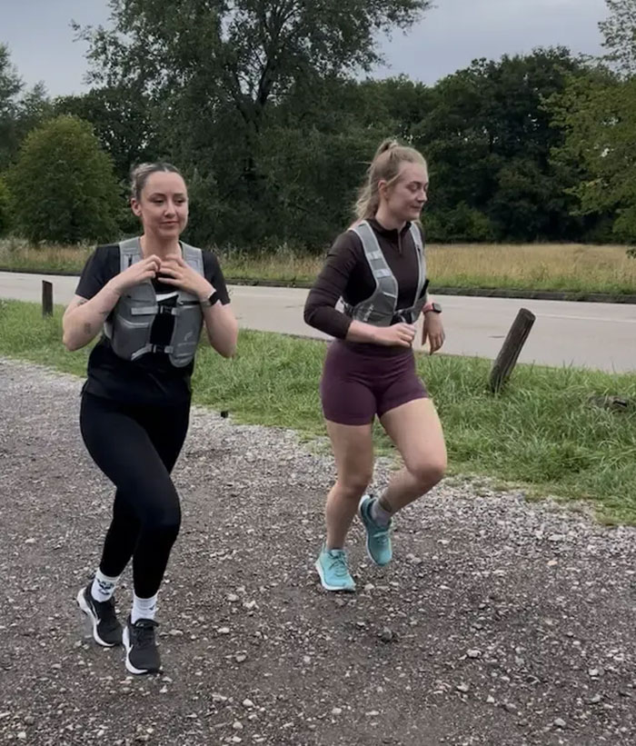Two women wearing running clothes and reflective vests jogging outdoors as part of cops using running clothes tactic.