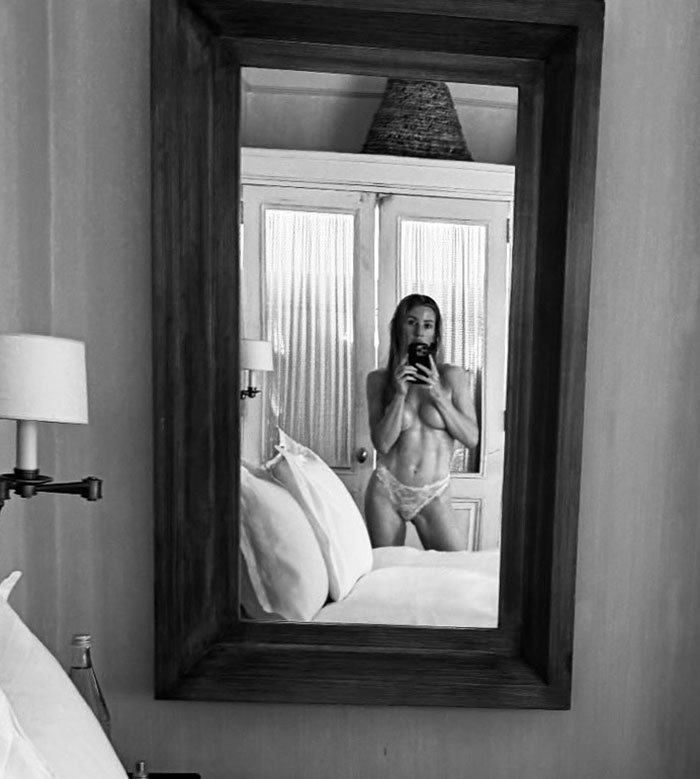 Ellie Goulding taking a racy mirror selfie in lingerie, sparking fan reactions amid ongoing romance rumors.