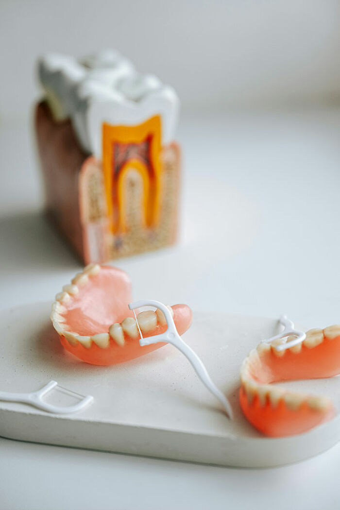 Dental floss and dentures on white surface, representing a tiny habit that could help prevent heart attack and dementia.