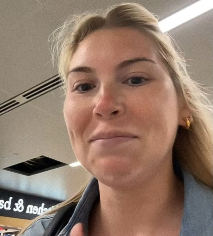 Woman in airport with a slight smile during a heated debate after passenger confrontation over bag watching. Woman in airport with a slight smile during a heated debate after passenger confrontation over bag watching.