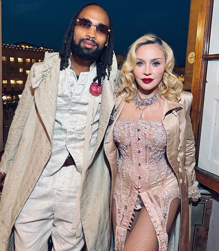 Madonna and a man posing together at an event, with Madonna wearing a detailed corset outfit.