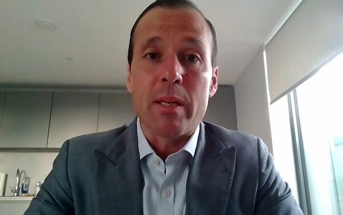 Man in a suit speaking in a video call, related to Uber driver incident involving service dog and CEO confrontation.