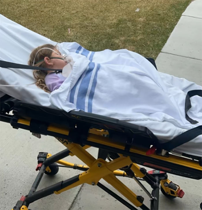 Child with medical oxygen lying on stretcher outside, highlighting family awarded nearly a billion dollars for gravely disabled baby.