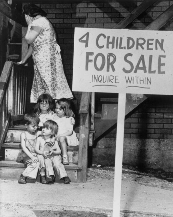 Four children sitting on worn steps near a woman covering her face, with a creepy sign saying "4 children for sale."