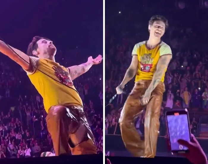 Celebrity wardrobe malfunction on stage with yellow shirt and brown pants during a live concert performance.