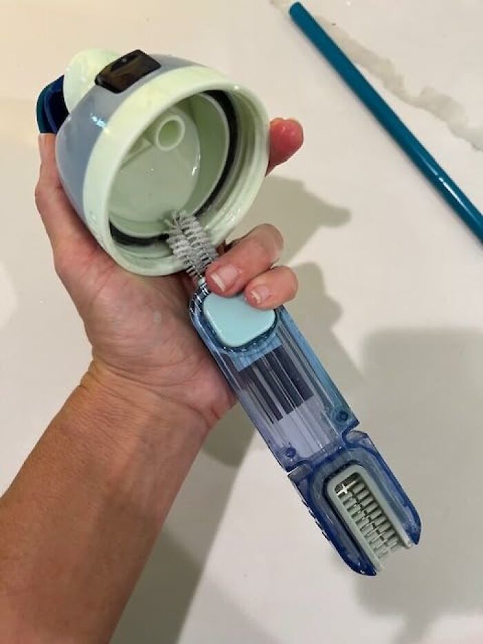 Hand holding a cleaning brush inside a bottle lid, demonstrating genius cleaning tricks to impress your in-laws effortlessly.
