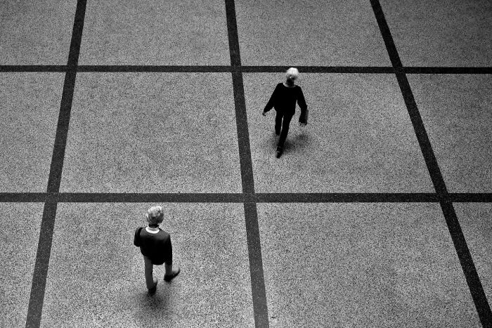 Two people walking on a grid-patterned street captured by a photographer showcasing unseen unposed moments.