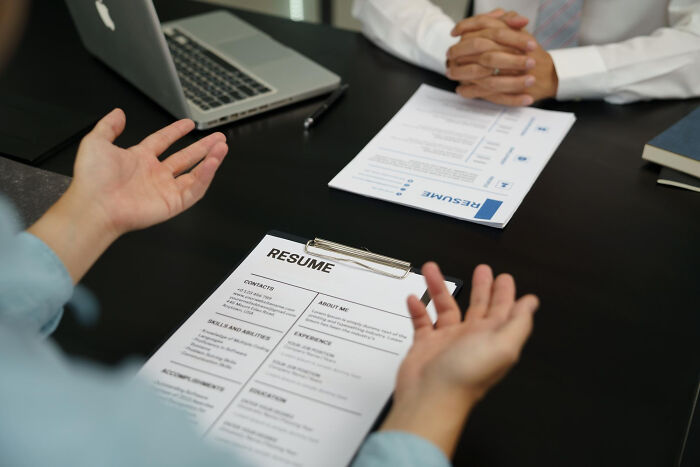 Two people in a job interview, discussing a resume and unhinged hacks to land a job successfully.