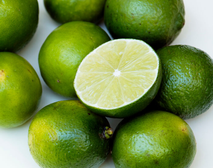 Close-up of fresh green limes with one cut in half, highlighting texture and juicy interior for smooth pickup lines concept.