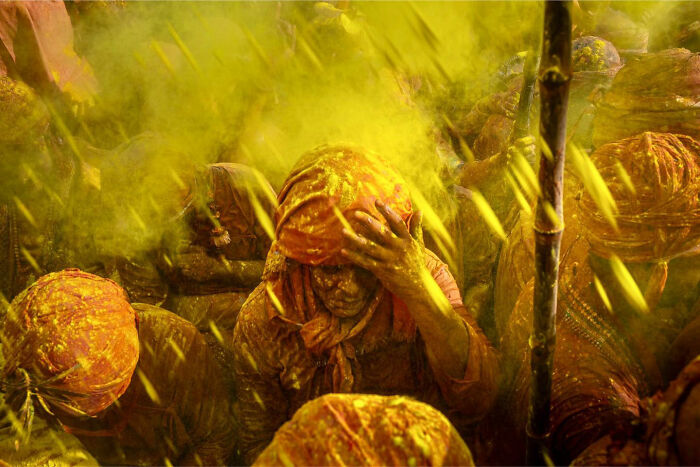 People covered in yellow powder during a vibrant candid everyday moment festival in Asia captured by photographer Gil Kreslavsky