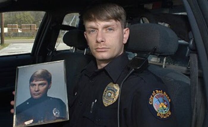 Police officer in uniform sitting in a car holding a framed photo of himself, part of unsettling images from Morbid Knowledge.