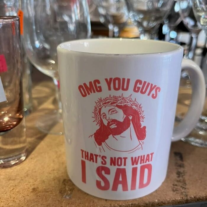 White mug with red Jesus graphic and humorous text found among glassware at a thrift store with bizarre items.