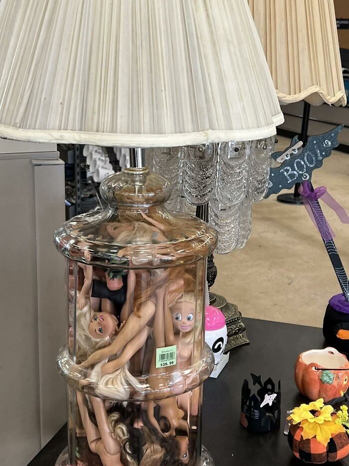 Lamp with a clear base filled with doll parts, showcasing a horrendous DIY craft project for craft shaming content.