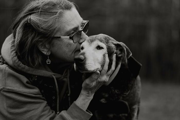 Woman tenderly holding her aging dog’s face outdoors, capturing touching final moments between pets and their humans.