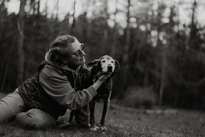 Woman tenderly holding her aging dog’s face outdoors, capturing touching final moments between pets and their humans.