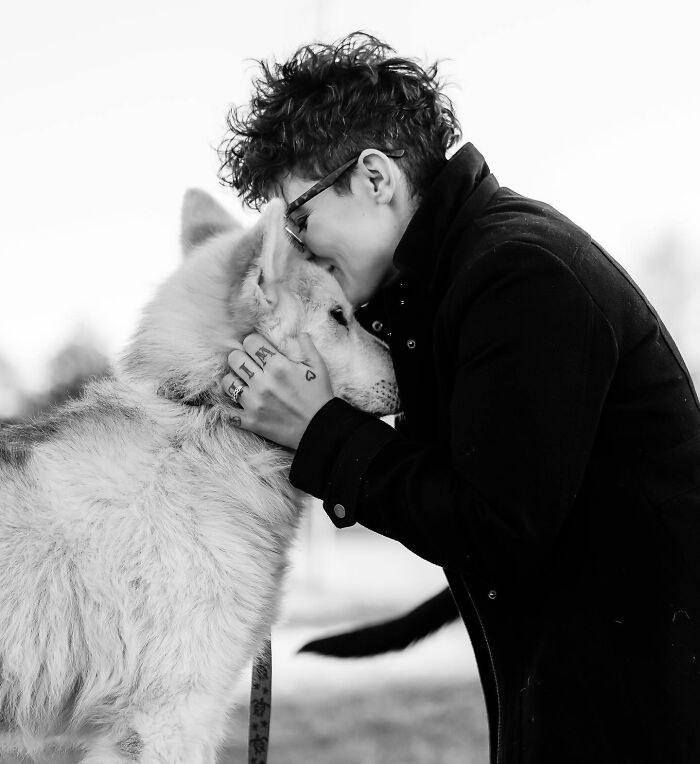 Person with short curly hair and glasses sharing a tender moment with a dog in touching photos capturing final moments between pets and humans