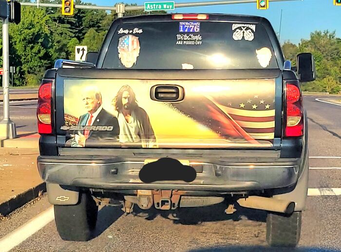Black pickup truck with a poorly executed custom paint job featuring political and religious imagery, a craft shaming example.