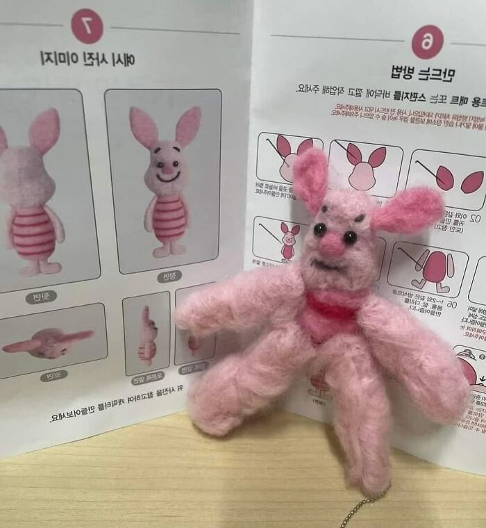 Felted pink bunny doll with extra limbs posed in front of its unusual thrift store instructions manual.