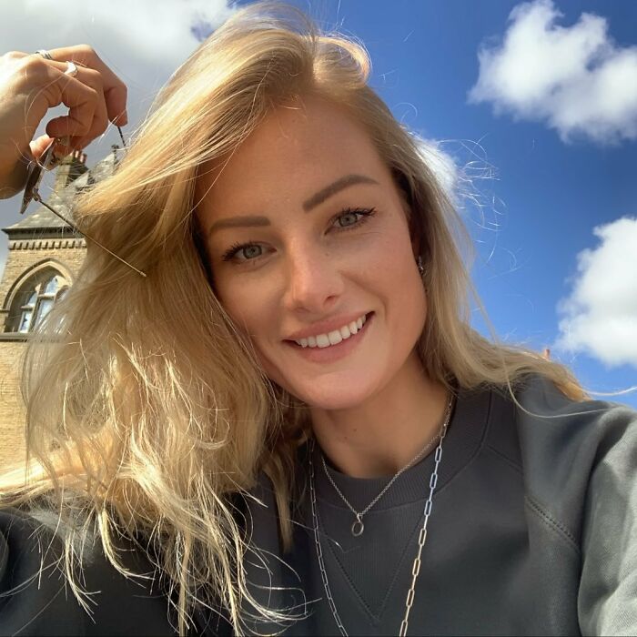 Smiling woman with blonde hair outside on a sunny day, representing woman’s 15,500-ft jump after breakup story. Smiling woman with blonde hair outside on a sunny day, representing woman’s 15,500-ft jump after breakup story.