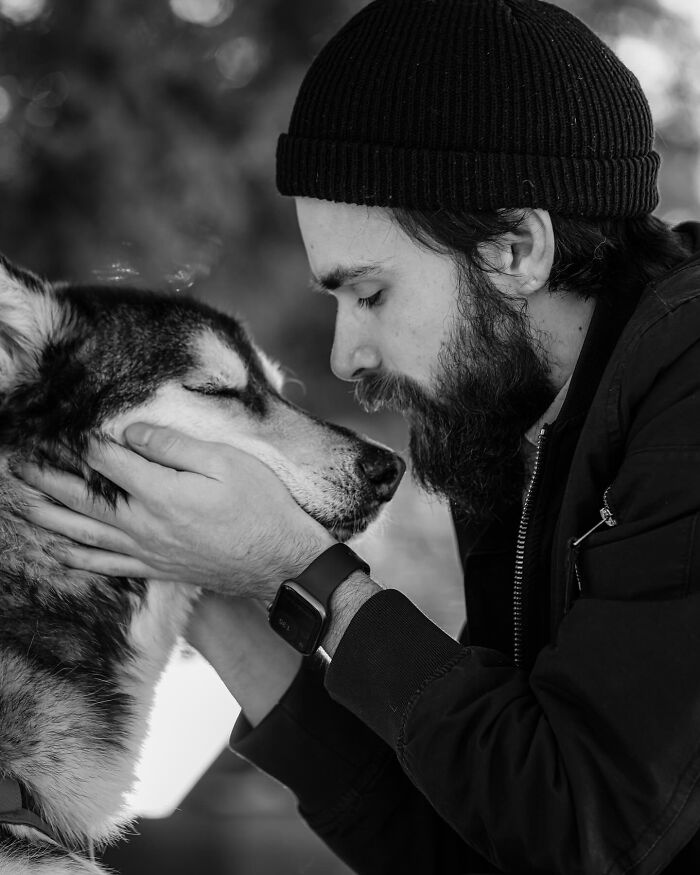 Black and white photo of a couple sharing a tender moment with their dog, capturing touching final moments between pets and humans.