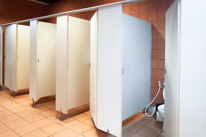 School bathroom stalls with white partitions and tiled floor showing a common setting for wild school kids' confident pranks.