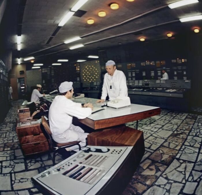 Workers in a dimly lit control room surrounded by vintage equipment, an unsettling image from Morbid Knowledge group.