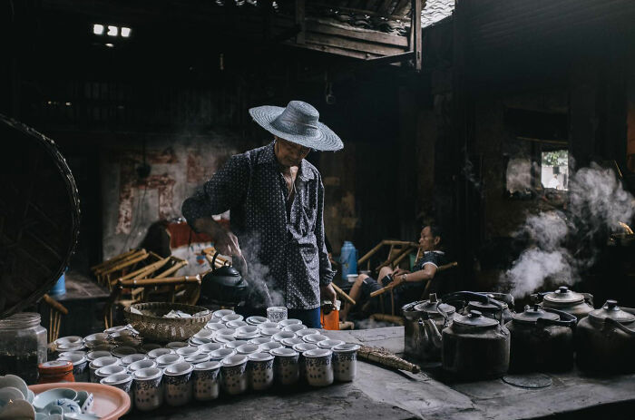 Man pouring tea in a traditional setting with steam rising, one of the candid everyday moments from Asia by Gil Kreslavsky.