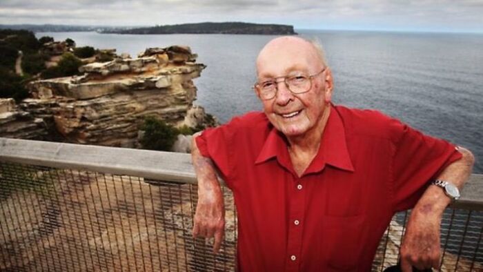 Elderly man in a red shirt smiling by a coastal cliff, an example among unsettling images from Morbid Knowledge group.