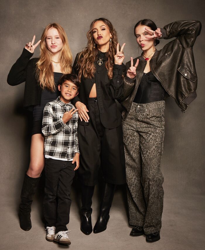 Jessica Alba posing with three young family members, all making peace signs and dressed in stylish casual outfits.