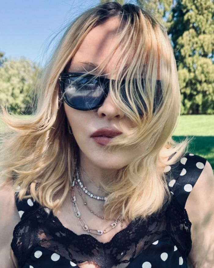 Blonde celebrity wearing sunglasses and layered necklaces posing outdoors, showing how out-of-touch celebs can be.