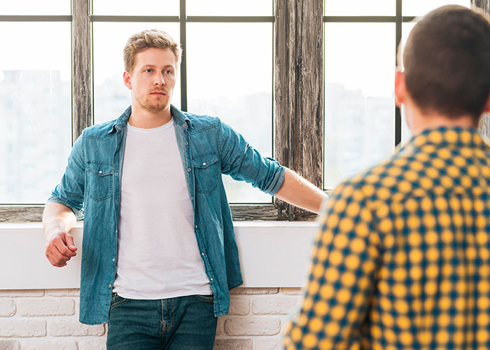 Young man looking concerned while talking to another person in a bright room, relating to food his dad has touched.