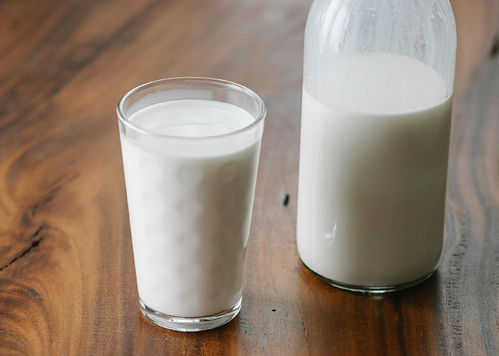 Glass of milk and a milk bottle on wooden table representing intern hospitalized after coworker brought cupcakes.