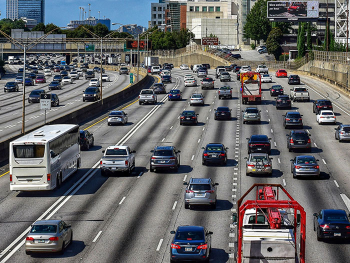 Busy multi-lane highway with cars and a white bus driving in clear weather, illustrating a bus-related incident scenario. - 7