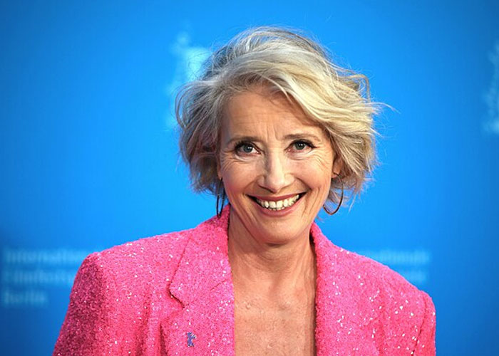 Actress smiling in a bright pink jacket at a celebrity event, capturing a total gentleman moment with fans.