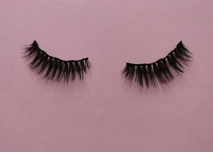 False eyelashes laid out on a pink background symbolizing wild and embarrassing drinking stories related to alcohol and poor decisions.