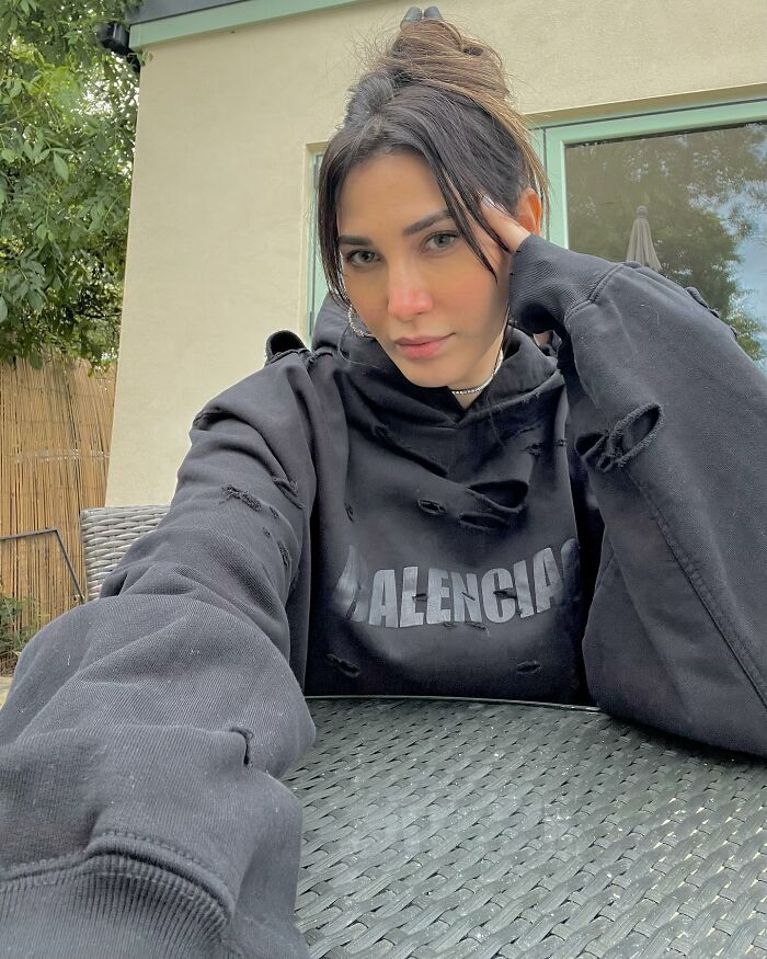 Supermodel wife posing outdoors in a torn black Balenciaga hoodie, reflecting on pain after intoxicated man's threat to flight attendant. Supermodel wife posing outdoors in a torn black Balenciaga hoodie, reflecting on pain after intoxicated man's threat to flight attendant.