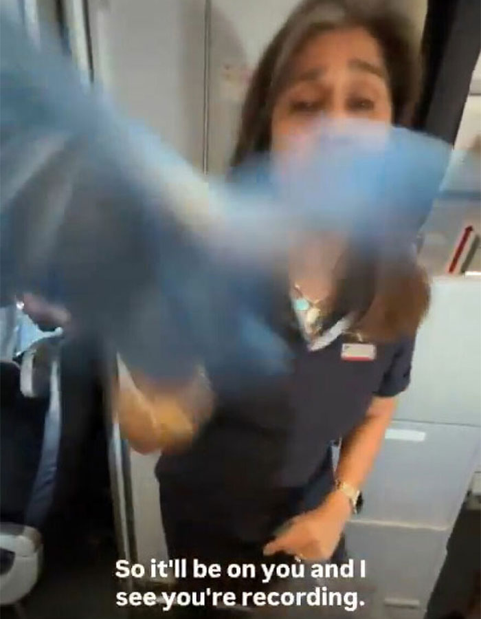 Flight attendant confronting man caught vaping on plane, engaging in heated exchange during the incident.