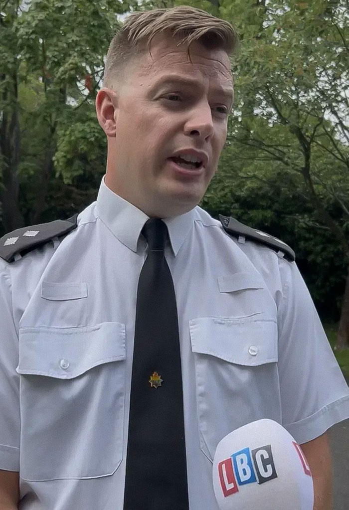 Police officer in uniform speaking outdoors with LBC microphone, related to cops wearing running clothes to elicit catcalls debate.