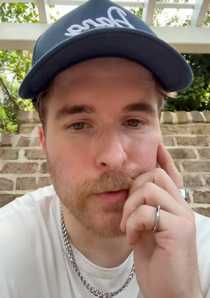 Young man wearing a cap and chain necklace, appearing thoughtful while discussing short king height preferences in dating.