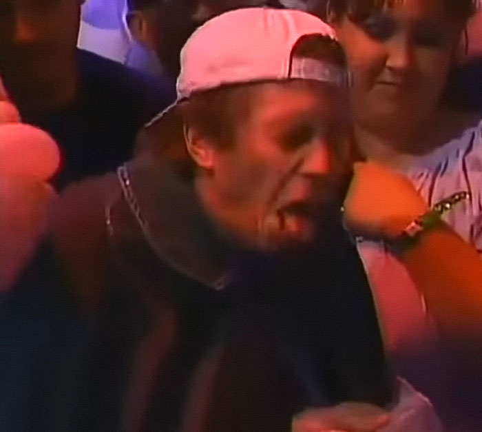 Man in a pink backwards cap reacting dramatically at an early 2000s ugliest woman contest crowd event. Man in a pink backwards cap reacting dramatically at an early 2000s ugliest woman contest crowd event.