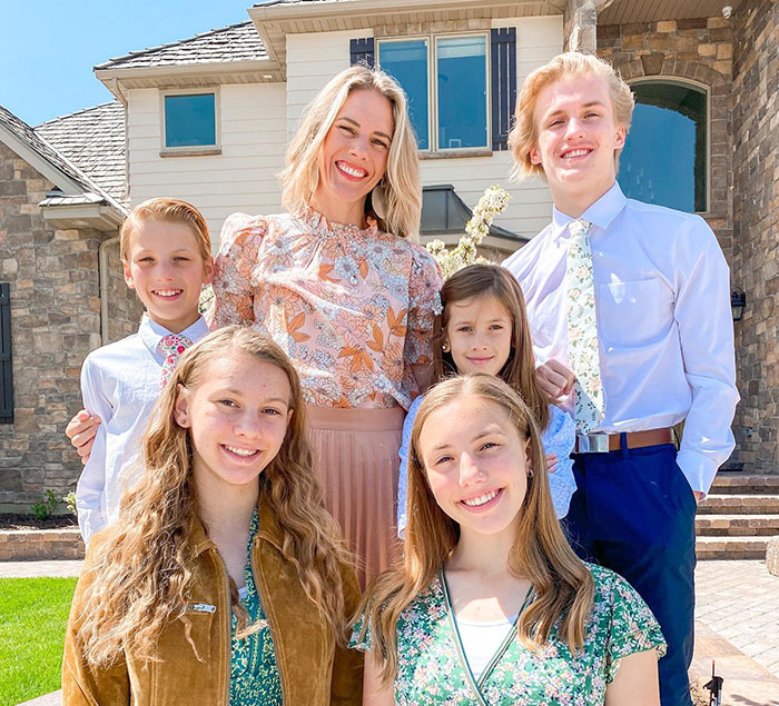 A smiling family of six standing outside a house, illustrating awareness of predators targeting children's social media.