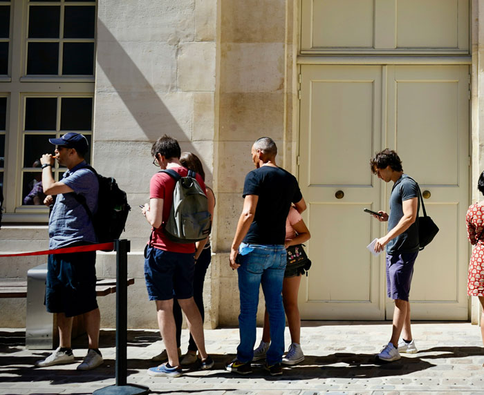 People standing in line outdoors, showcasing behaviors that make Americans stand out in a foreign country.