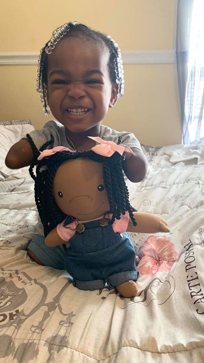 Happy child holds a custom doll representing rare health conditions, designed to fit each child's unique needs.