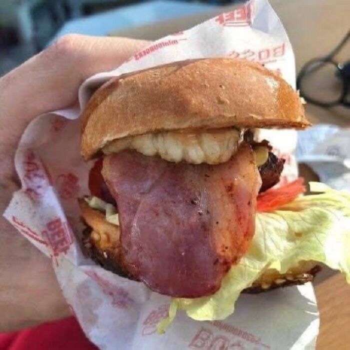 Burger with bacon and lettuce resembling a face with a protruding tongue, posted in a random objects that look like faces group.