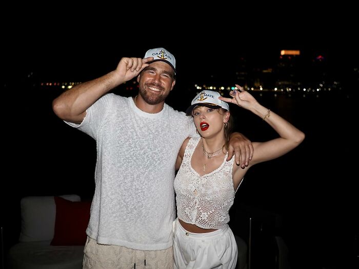 Travis Kelce and Taylor Swift smiling and posing together at night, sparking buzz involving Kayla Nicole.