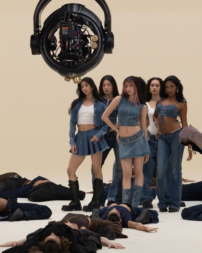Models wearing Gap jeans posing in a studio photoshoot with others lying on the floor, showcasing denim fashion campaign.